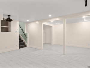 Finished basement with recessed lighting, baseboards, wood finished floors, and stairs