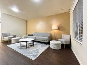 Living room featuring wood finished floors, baseboards, and a textured ceiling