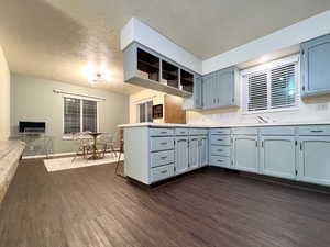 Kitchen with dark wood finished floors, a peninsula, blue cabinets, and light countertops
