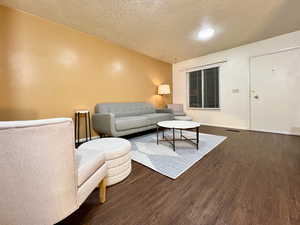 Living room with a textured ceiling, baseboards, and wood finished floors