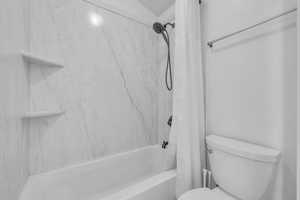 Bathroom with toilet and shower / bath combo with shower curtain