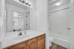 Full bath with shower / bathing tub combination, toilet, wood finished floors, and vanity