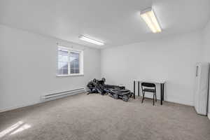 Exercise room featuring a baseboard radiator, carpet floors, and a textured ceiling