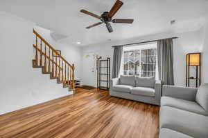 Living area featuring visible vents, crown molding, baseboards, stairway, and light wood-style floors