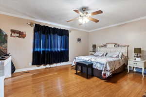 Bedroom with visible vents, wood-type flooring, baseboards, and crown molding