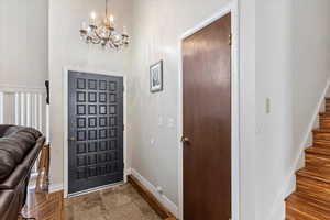 Entrance foyer with a notable chandelier, stairs, and baseboards