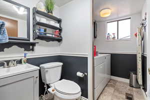 Bathroom with visible vents, baseboards, toilet, washer and dryer, and vanity