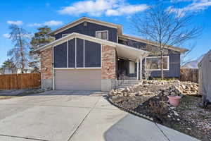 Mid-century inspired home with brick siding, concrete driveway, a garage, and fence
