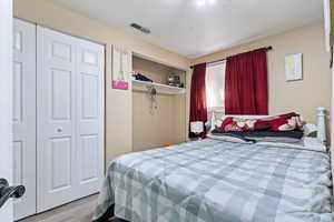 Bedroom featuring wood finished floors, visible vents, and a closet