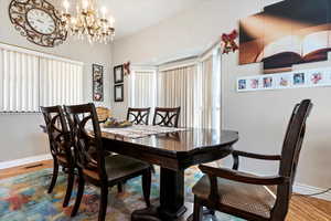 Dining area featuring an inviting chandelier, wood finished floors, visible vents, and baseboards