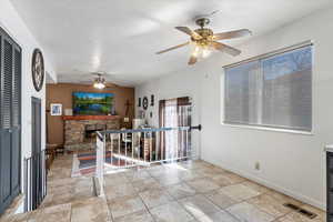 Interior space featuring visible vents, a ceiling fan, light tile patterned flooring, a fireplace, and baseboards