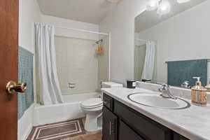 Full bath with tile patterned floors, toilet, shower / bath combo, and vanity
