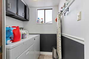 Laundry area featuring light tile patterned floors, baseboards, cabinet space, and washing machine and dryer