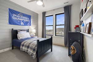 Bedroom with visible vents, wooden walls, baseboards, light colored carpet, and ceiling fan