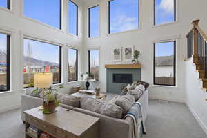 Living area featuring a glass covered fireplace, stairway, carpet flooring, and a wealth of natural light looking Southeast.