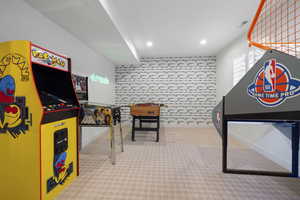 Recreation room with recessed lighting, carpet, visible vents, and brick wall.