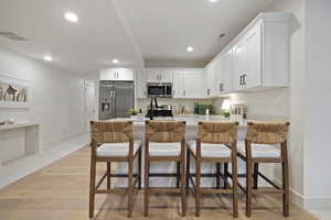 Kitchen featuring light countertops, light wood finished floors, recessed lighting, and appliances with stainless steel finishes