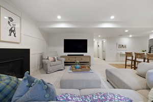 Living area featuring light carpet, a decorative wall, recessed lighting, and a fireplace