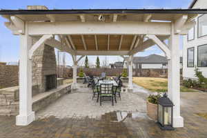 View of patio / terrace with a gazebo, outdoor dining space, an outdoor stone fireplace, and fence