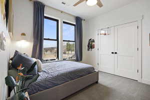 Carpeted bedroom with a closet, visible vents, and ceiling fan