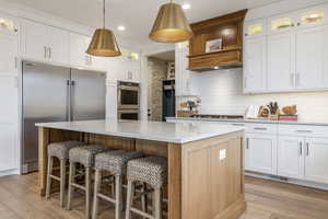 Kitchen with stainless steel appliances, decorative backsplash, a center island, and light wood finished floors