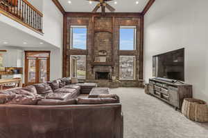 Carpeted living room featuring ceiling fan, ornamental molding, recessed lighting, a fireplace, and a towering ceiling