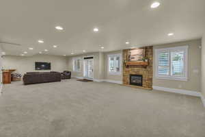 Living room with light carpet, a stone fireplace, recessed lighting, and a wealth of natural light