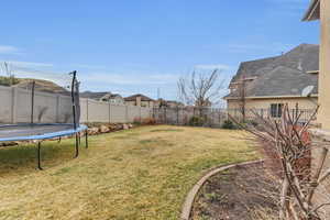 View of yard with a trampoline and a fenced backyard