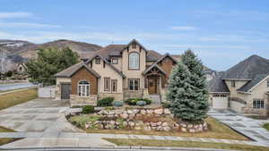 View of front of house with stucco siding, concrete driveway, a garage, stone siding, and a mountain view