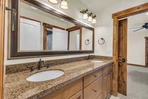 Full bath with double vanity, a ceiling fan, baseboards, and a sink