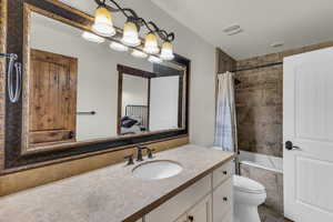 Bathroom featuring visible vents, a chandelier, toilet, tiled shower / bath combo, and vanity