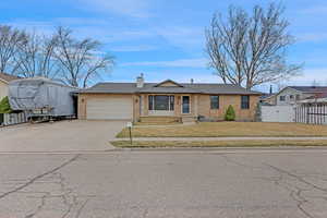 View of front of house featuring a front yard, fence, a chimney, a garage, and brick siding