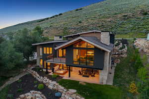 Back of property with a chimney, a patio area, and stone siding