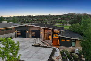 Modern home with stone siding, a garage, concrete driveway, and a mountain view