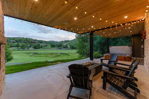 View of patio / terrace featuring a hot tub, a mountain view, an outdoor fire pit, and view of golf course
