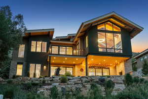 Back of property featuring a balcony and stone siding