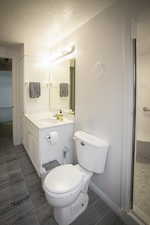 Bathroom with wood finish floors, toilet, a textured ceiling, baseboards, and vanity