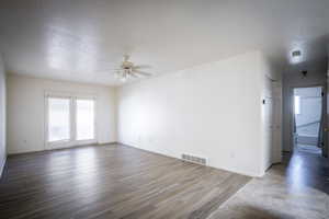 Empty room with wood finished floors, a ceiling fan, visible vents, and baseboards