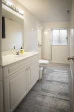 Full bathroom with toilet, a stall shower, a textured ceiling, vanity, and wood tiled floor