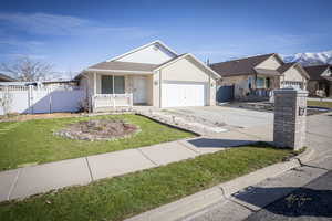 View of front of property with fence, driveway, an attached garage, covered porch, and brick siding