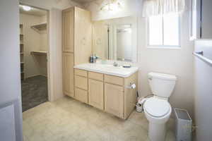 Master Bathroom with toilet, a spacious closet, and vanity