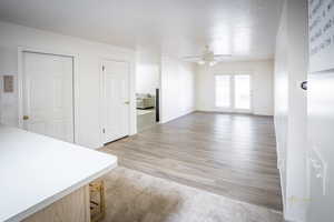 Unfurnished living room with light wood-style flooring and a ceiling fan