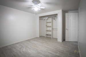 Unfurnished bedroom with a ceiling fan, baseboards, and wood finished floors