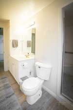 Full bathroom featuring vanity, baseboards, wood tiled floor, a textured ceiling, and toilet