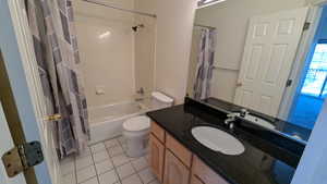 Full bathroom with toilet, shower / bath combination with curtain, vanity, and tile patterned flooring