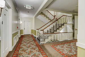 Carpeted entrance foyer with stairway, baseboards, and ornamental molding