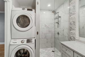 Laundry area featuring stacked washer and dryer, light wood-style flooring, and laundry area