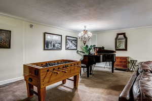 Game room with crown molding, a notable chandelier, carpet floors, and a textured ceiling