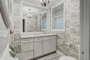 Bathroom featuring a chandelier, wallpapered walls, and vanity