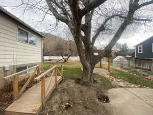 View of yard featuring a greenhouse, an outbuilding, a fenced backyard, and a playground